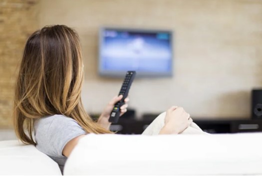 Woman Holding TV Remote Control With TV ON