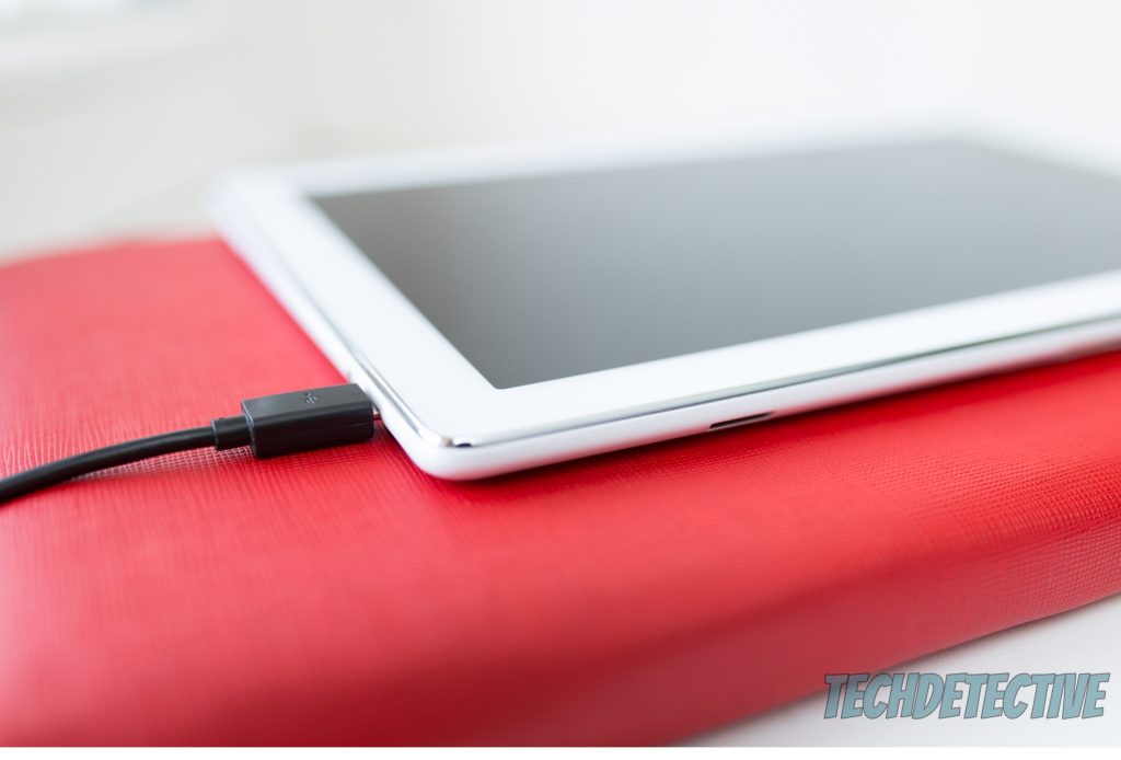 A Kindle with a charging cable plugged in