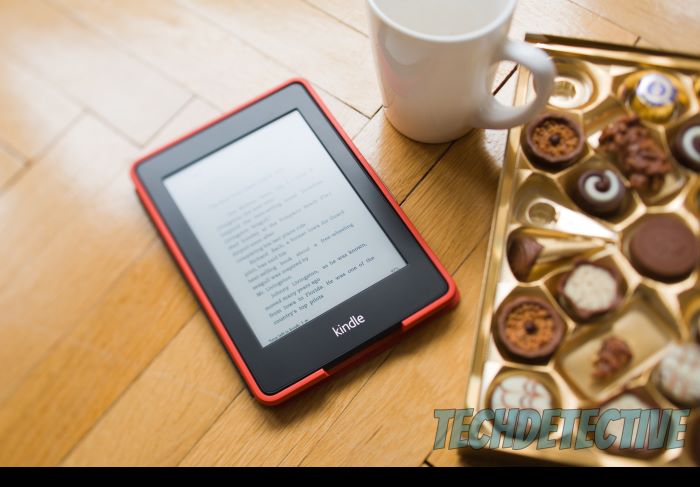 An Amazon Kindle next to a cup of coffee and assorted cookies